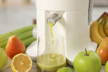 Modern juicer, fruits and glass on white table, closeup