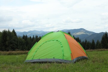 Tent on green grass in mountains. Camping equipment