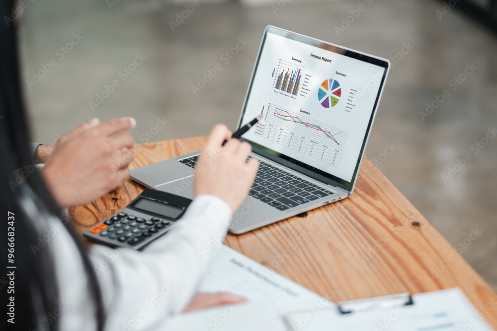Poster Two business professionals discussing financial data displayed on a laptop screen with charts and graphs, using a calculator and documents.