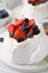 Pavlova cake (meringue dessert) with whipped cream and fresh berries on table, closeup