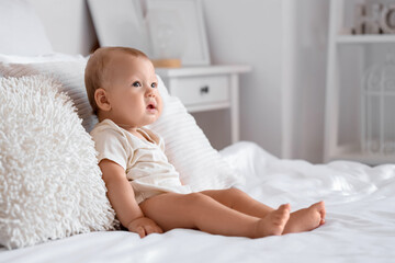 Cute little baby sitting on bed in room at home