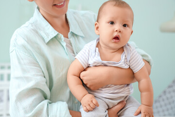 Beautiful young happy mother with cute little baby in children's room at home