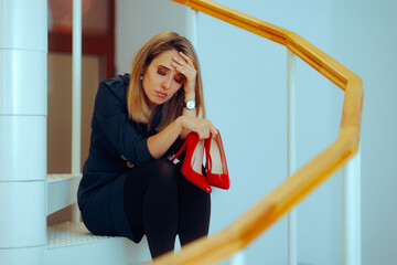 Tired Businesswoman Talking off her High Heels at Work. Sad stressed woman feeling exhausted and...