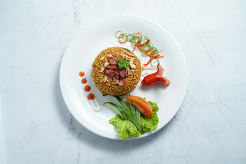 A Plate of Nasi Goreng With Rice, Vegetables, and Sausage on Marble Table
