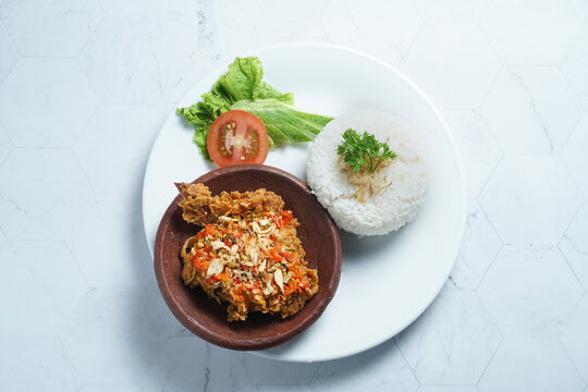 Ayam geprek is a typical Indonesian dish of fried chicken with flour that is mashed or mashed with plow chili sauce.