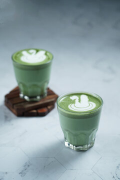 Cup of Matcha Latte With Latte Art on White Marble Table