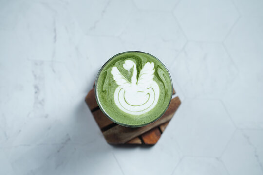 Cup of Matcha Latte With Latte Art on White Marble Table