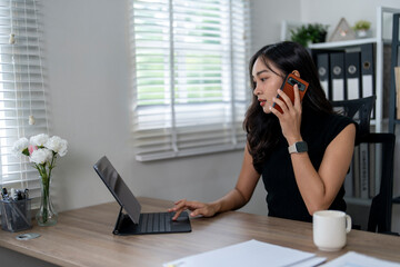 Obraz premium Businesswoman multitasking using phone and laptop in home office