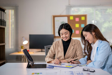 Two young businesswomen analyzing financial data in modern office