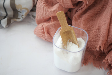 Baking soda in a container and cloths on table 