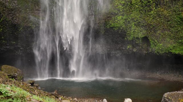 Slow motion landscape of secluded running waterfall Multnomah Falls water stream river surrounded by mossy rocks Oregon forest Portland USA America nature travel tourism