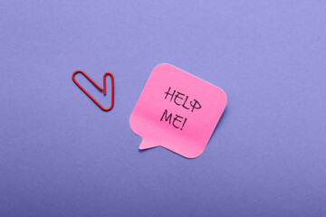A red paperclip is on a blue background with a pink note that says Help Me!