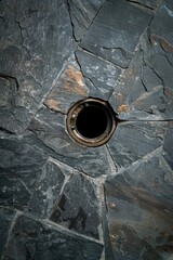 Close-up of a round hole in a stone wall.