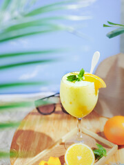 cold and refreshing juice on a glass in a summer afternoon on the beach.  served on the table with sliced fruits and mint leaves. holiday season in summer.
