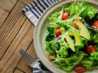 Healthy assorted vegetable salad with avocados and tomatoes, served in a bowl with diced cheese and an option of olive oil

