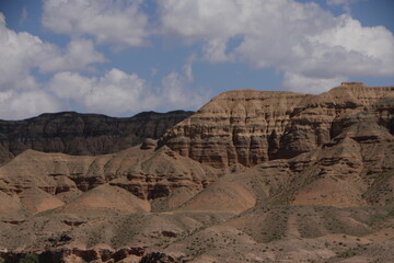 Canyon cliffs under a blue sky with clouds.