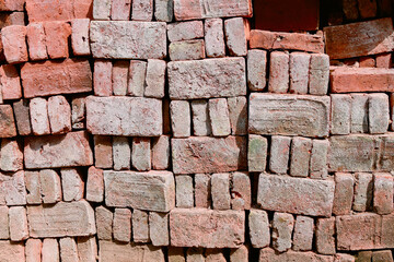 Red bricks stacked at a construction site, close-up. The bare brick walls of an unworthy house.