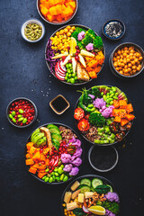 Vegan buddha bowls set for balanced diet with vegetables, quinoa, soybeans, tofu and seeds, black background, top view.