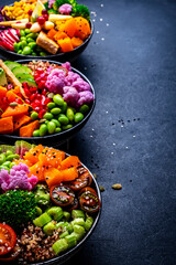 Vegan buddha bowls set for balanced diet with vegetables, quinoa, soybeans, tofu and seeds, black background, top view.
