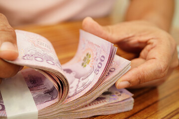 Asian woman counting Thai baht banknote money and holding in hand, investment economy, accounting...