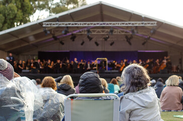 Close-up of unidentified audiences at an outdoor orchestra concert, sitting outside in cold weather...