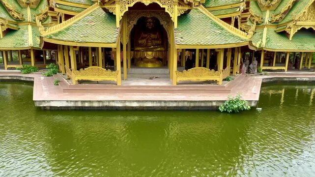 4K video footage of Pavilion of the Enlightened, a green temple complex in Muang boran Ancient city, Samut Prakan, Bangkok, Thailand. Famous green and gold roof structure, surrounded by a lake.