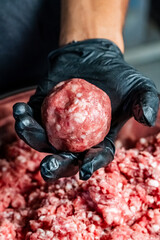 a chef forming a ball of ground beef patty by hand