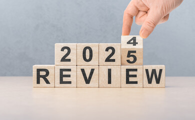 2025 review new year. hand turns wooden cube and changes number Review 2024 to Review 2025....