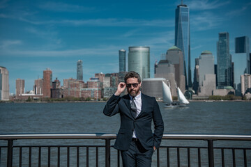 Confident rich business man executive standing in New York City. Business American success. American business dream. American businessmen in suits near Manhattan. Successful business in USA.