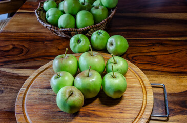 Green apples on a wooden cutting board sitting on a wooden table