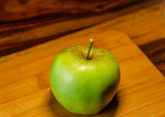 Single green apple on a wooden chopping board