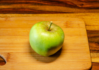 Single green apple on a wooden chopping board