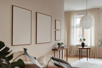 Blank wooden frame mockups in nordic contemporary scandinavian living room interior. Empty template of four posters, wall arts mock up din A ratio, home interior in beige tones, white wall background