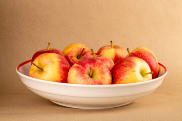 Several red apples on a ceramic plate on kraft paper, macro.