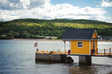 Bright yellow fishing stage building at edge of ocean in Newfoundland.
