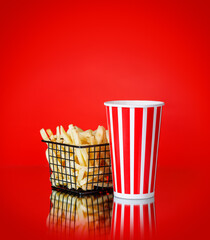 French fries and a cup of cola on a red background