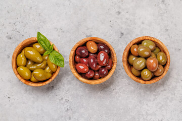 An assortment of various olives presented in a bowl, showcasing different colors, textures, and...