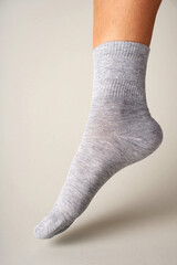 Man foot with sock on gray background. Feet with grey cotton sock, close-up. 