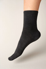 Man foot with sock on gray background. Feet with grey cotton sock, close-up. 