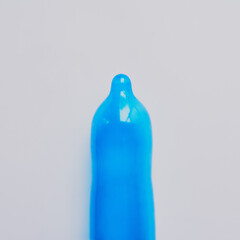 Blue, condom or latex in studio for education, sexual health or STD awareness. Contraception,...