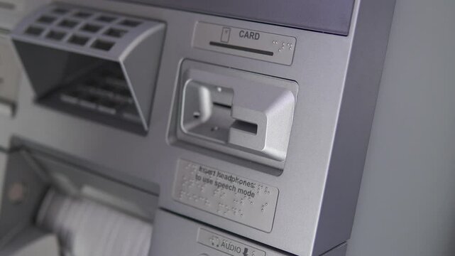 Close up of a person using ATM, inserting card pressing number pin button and taking out card.