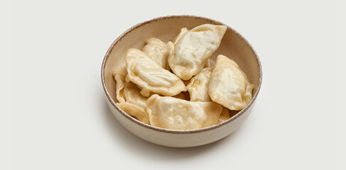 A bowl of traditional Ukrainian varenyky is presented on a beige plate against a clean white background.