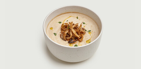 A bowl of creamy mushroom soup is presented on a white background. The soup is topped with crispy fried mushrooms and a drizzle of olive oil.