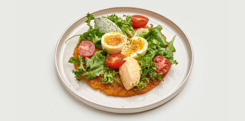 A modern take on a traditional Ukrainian dish, deruny. Served on a white plate, the potato pancake is topped with a poached egg, fresh salad, and a drizzle of sauce.