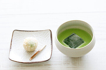 Cup of fresh matcha tea, green tea and Japanese confectionary on white wooden table.