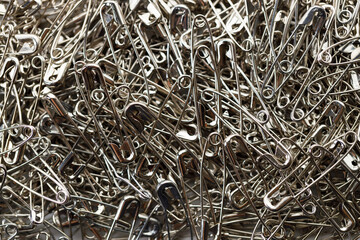 A number of stainless safety pins on white background.