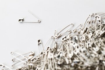 Fototapeta premium A number of stainless safety pins on white background.