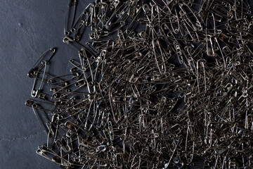 A number of stainless safety pins on black stone background.