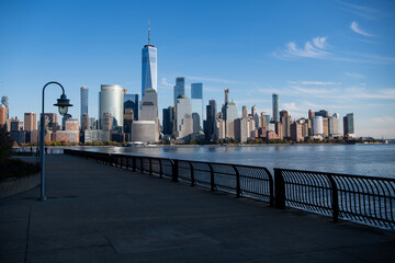 Obraz premium Lower Manhattan and One World Trade Center in New York City, USA as seen from Weehawken New Jersey. Skyscrapers of Manhattan located near rippling water of New York bay against blue sky.
