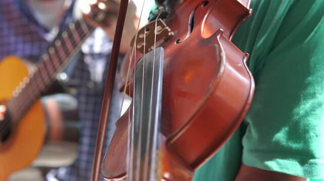 Busker group of men playing violin music instrument to entertain people.